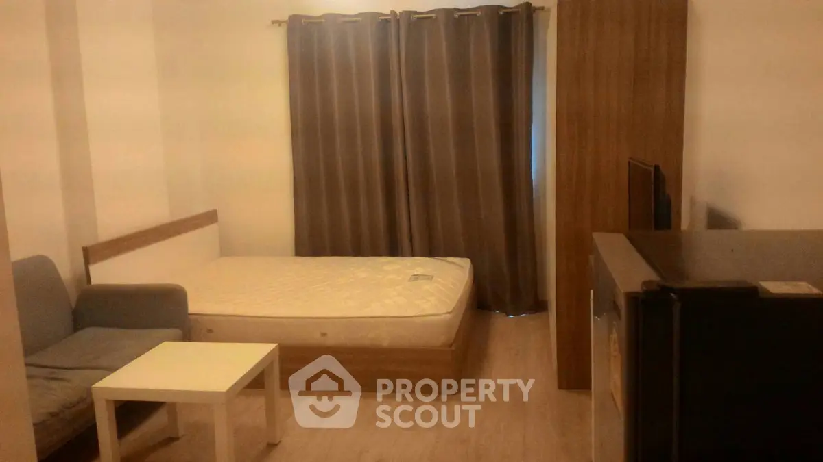 Cozy studio apartment with bed, sofa, and curtains, ideal for urban living.