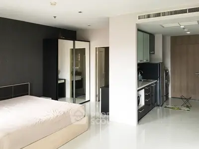 Modern studio apartment with sleek kitchen and spacious bedroom area.