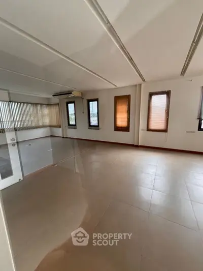Spacious empty room with large windows and tiled flooring, perfect for customization.