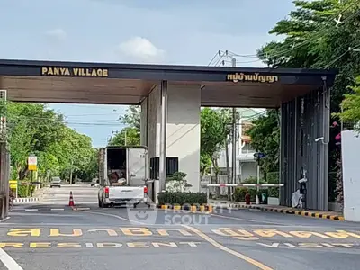 Entrance to Panya Village residential community with lush greenery and secure gated access.