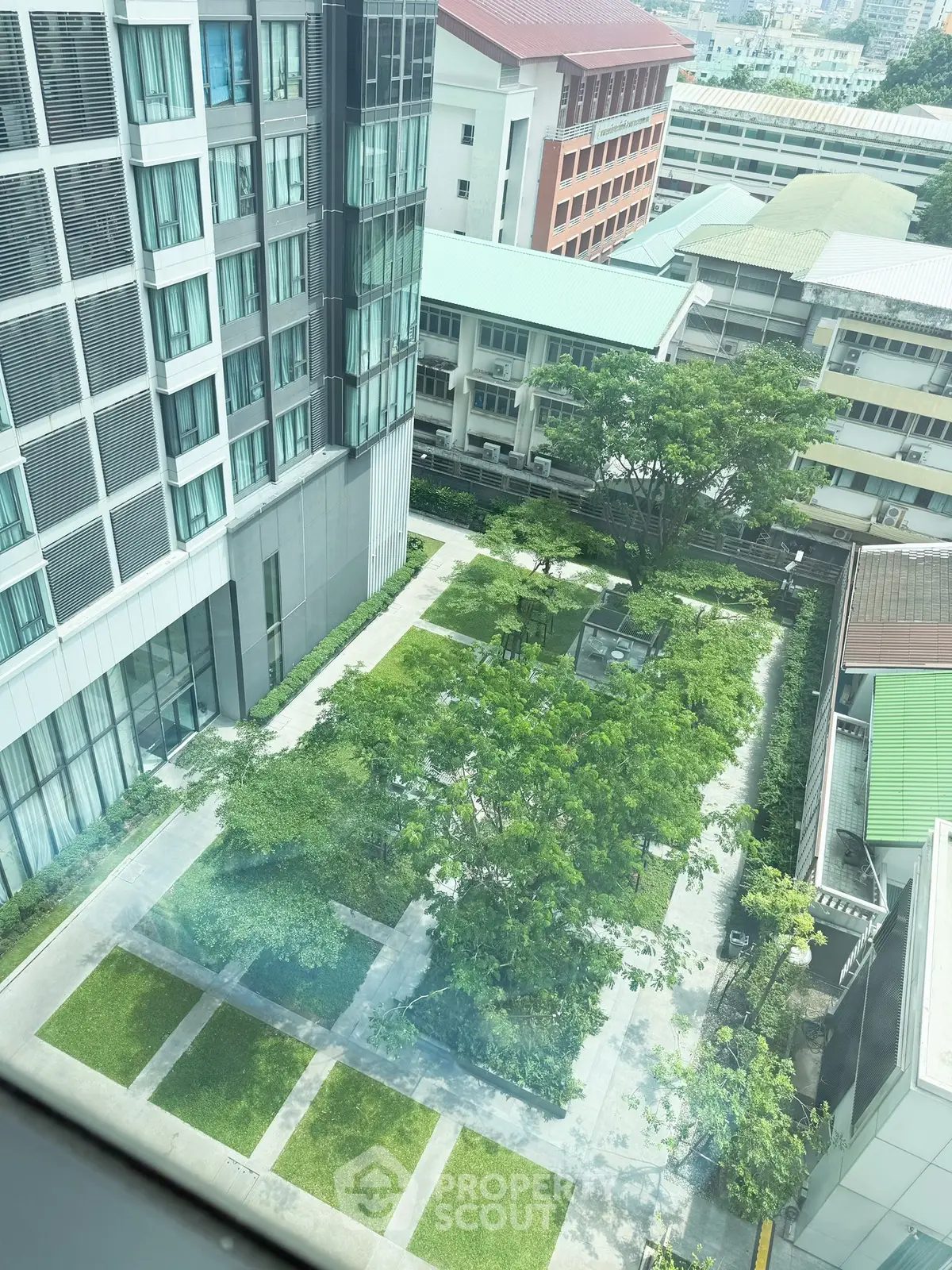 Stunning aerial view of modern building with lush green garden courtyard, perfect for urban living.