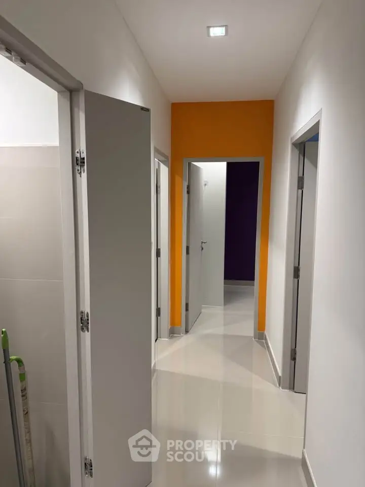 Modern hallway with vibrant accent wall and sleek doors in a contemporary home.