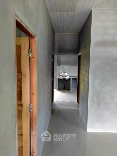 Modern minimalist hallway leading to a sleek kitchen area with polished concrete floors.