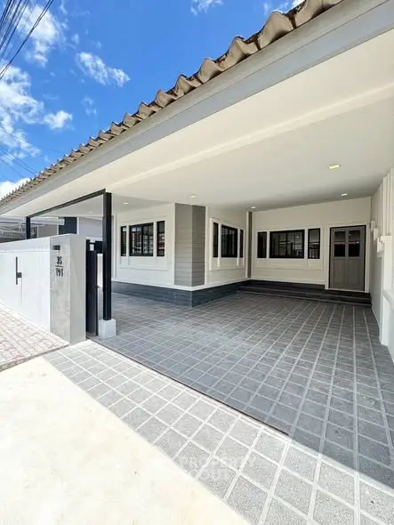 Modern house exterior with spacious driveway and tiled roof under clear blue sky.