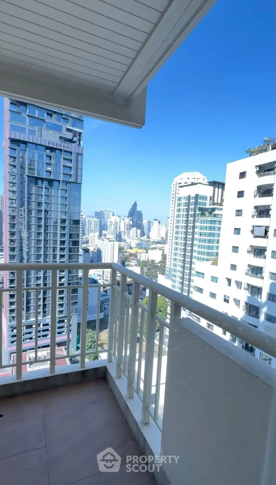 Stunning cityscape view from a high-rise balcony with modern skyscrapers under a clear blue sky.