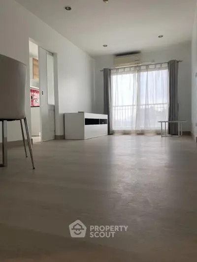 Spacious minimalist living room with natural light and modern furnishings.