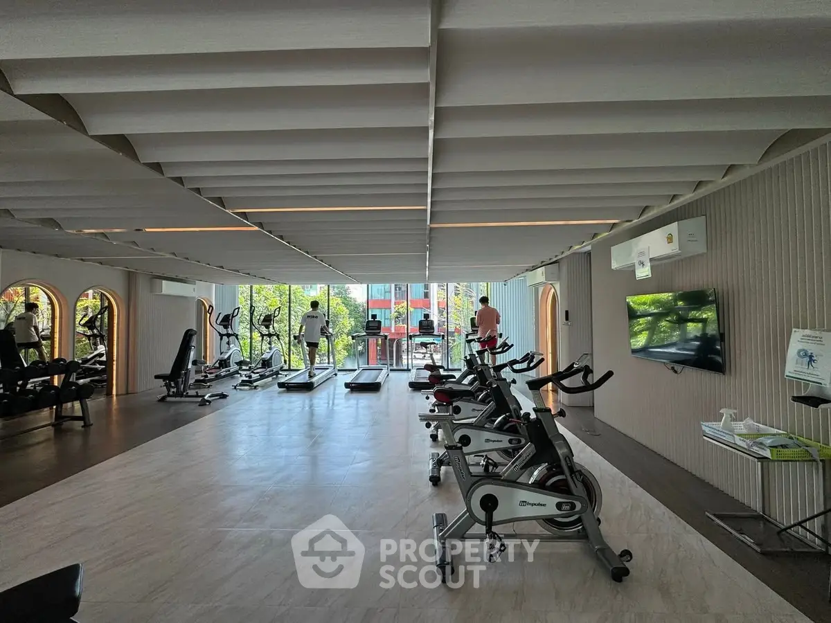 Spacious modern gym with state-of-the-art equipment and large windows offering a scenic view.