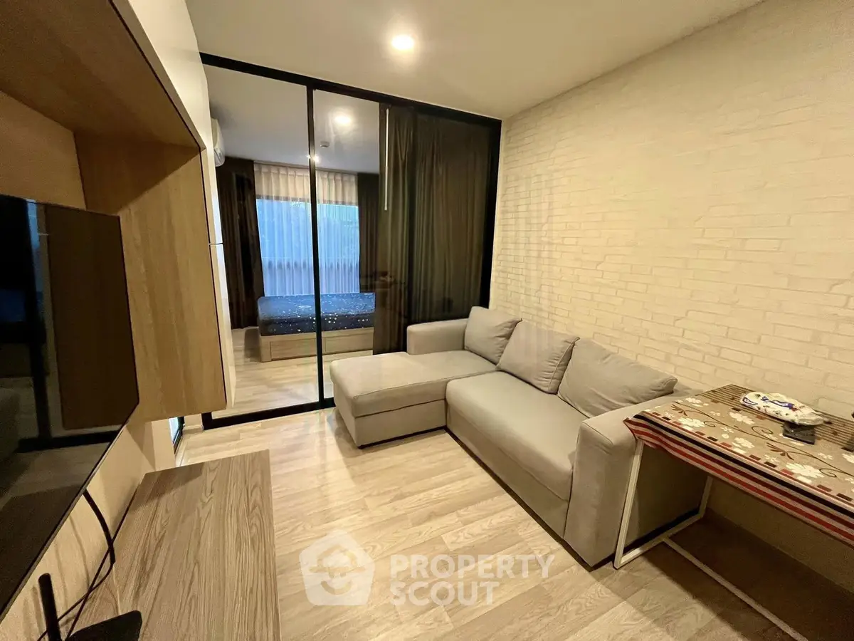 Modern living room with cozy sofa and sliding glass doors leading to bedroom