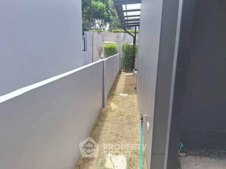 Narrow outdoor passageway between modern buildings with minimalistic design.