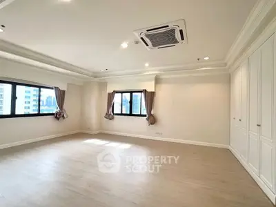 Spacious empty room with large windows and elegant ceiling design in modern apartment.