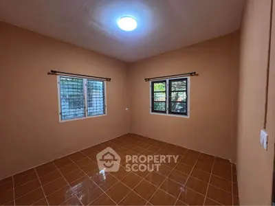 Spacious empty room with tiled floor and two windows, perfect for customization.