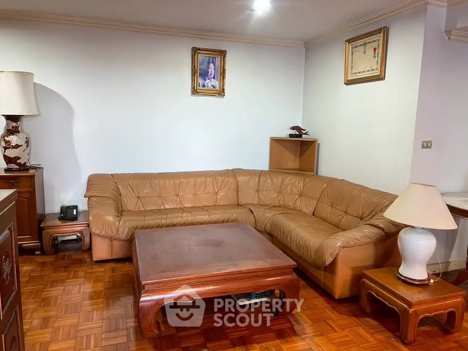 Spacious living room with elegant leather sofa and wooden furniture, perfect for relaxation and entertaining.