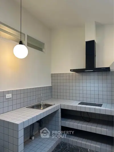 Modern minimalist kitchen with tiled countertops and sleek black range hood