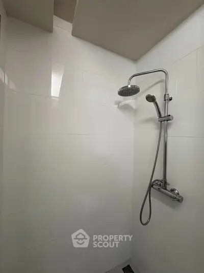 Modern bathroom shower with sleek chrome fixtures and white tiled walls.