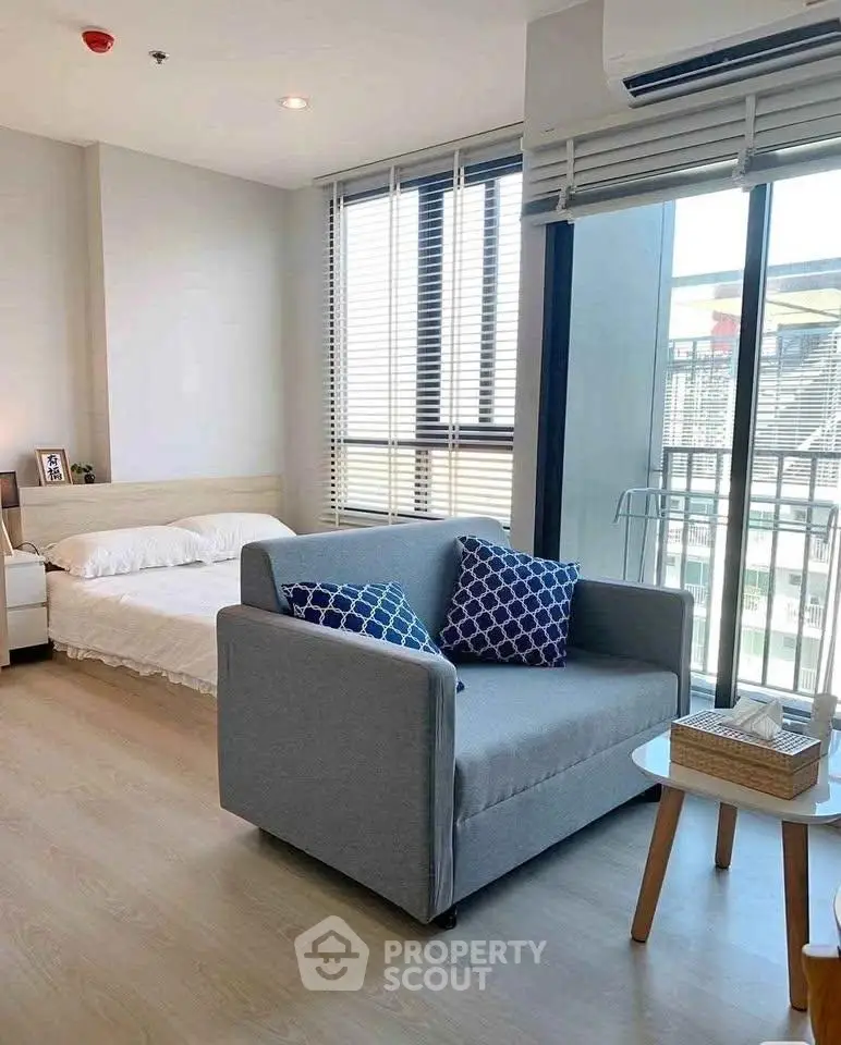 Modern studio apartment with cozy living area and large windows for natural light.