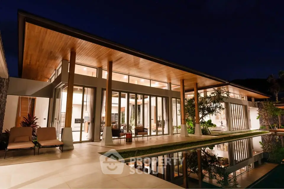 Luxurious modern villa with expansive glass walls and serene pool at night