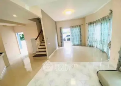 Spacious living room with elegant staircase and large windows for natural light