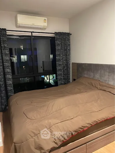 Cozy bedroom with modern decor and large window offering natural light.