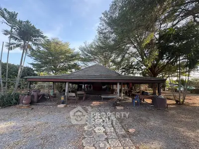 Charming rustic house with open-air design surrounded by lush greenery and mature trees, perfect for nature lovers.