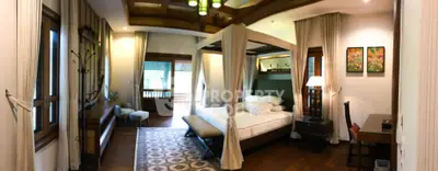 Luxurious master bedroom with elegant four-poster bed, rich wooden flooring, and cozy sitting area, perfect for upscale living.