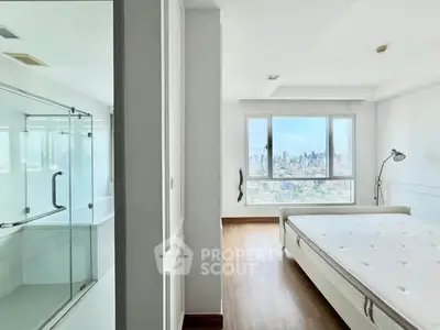 Modern bedroom with city view and adjacent glass shower