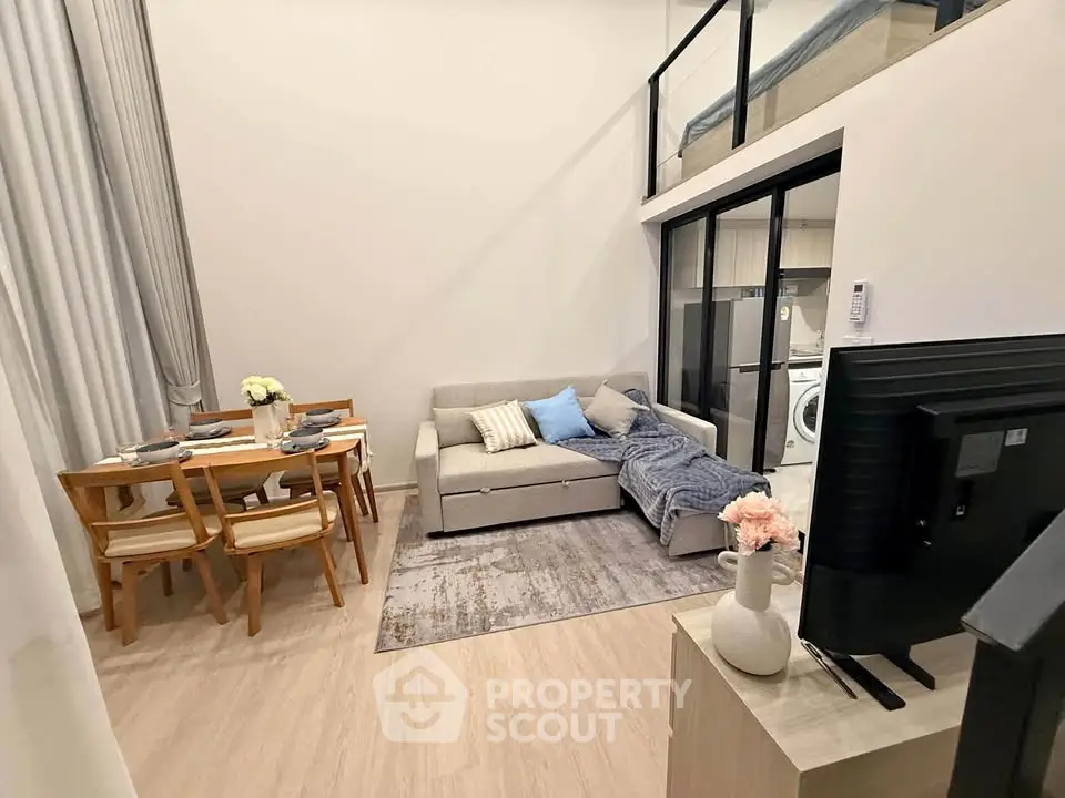 Modern living room with loft, cozy sofa, dining area, and stylish decor in open-concept apartment.