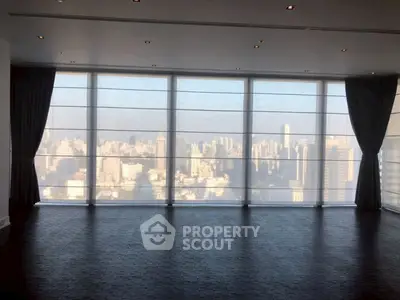 Spacious room with floor-to-ceiling windows offering stunning city skyline views.