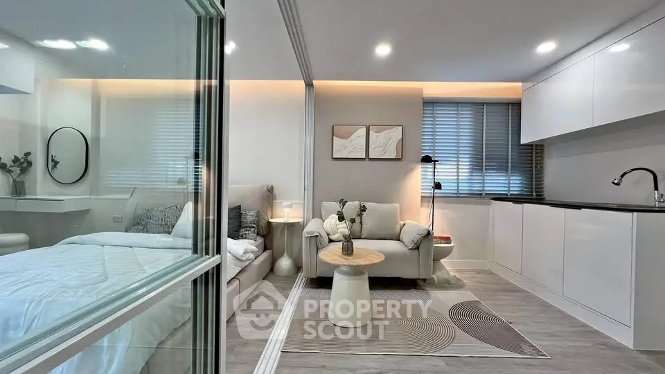 Modern studio apartment with sleek kitchen and cozy living area, featuring stylish decor and ample natural light.