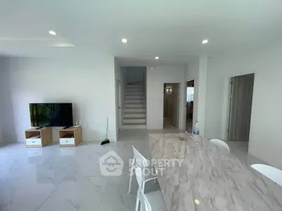 Modern open-plan living area with sleek marble dining table and minimalist decor