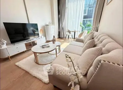 Elegant living room with plush sofa, large TV, and natural light from floor-to-ceiling windows.