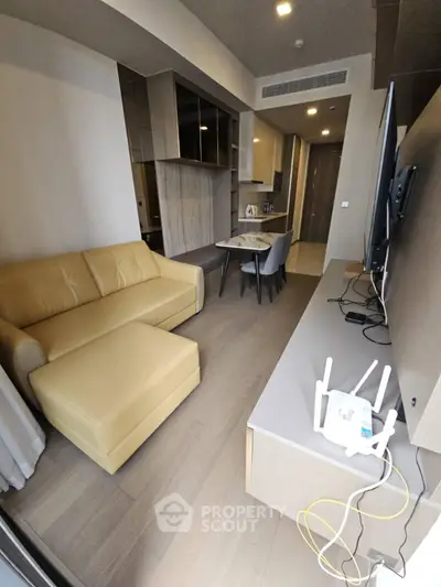 Modern living room with beige sofa, dining area, and TV setup in a stylish apartment.