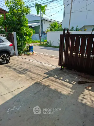 Spacious driveway with gated entrance and street view in a residential area.