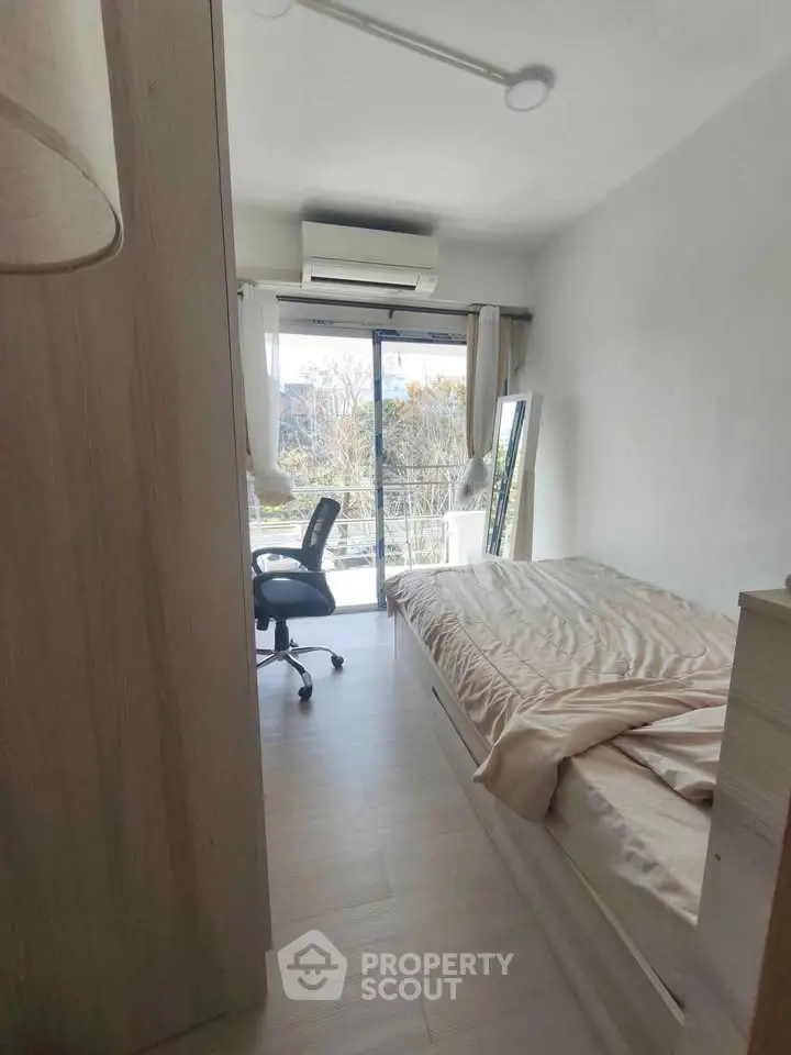 Cozy bedroom with natural light and balcony access, perfect for serene living.