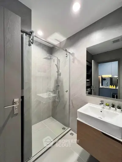 Modern bathroom with sleek shower and stylish vanity in contemporary apartment.