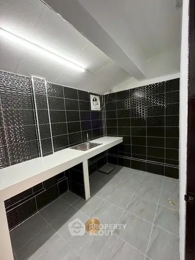 Modern bathroom with sleek black tiles and white countertop in contemporary home.