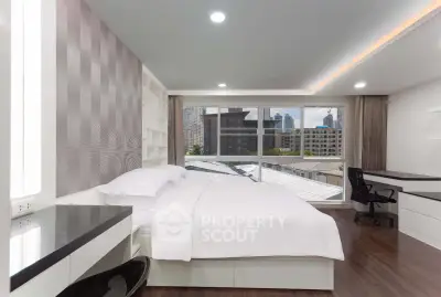 Modern bedroom with city view, featuring sleek furniture and large windows for natural light.