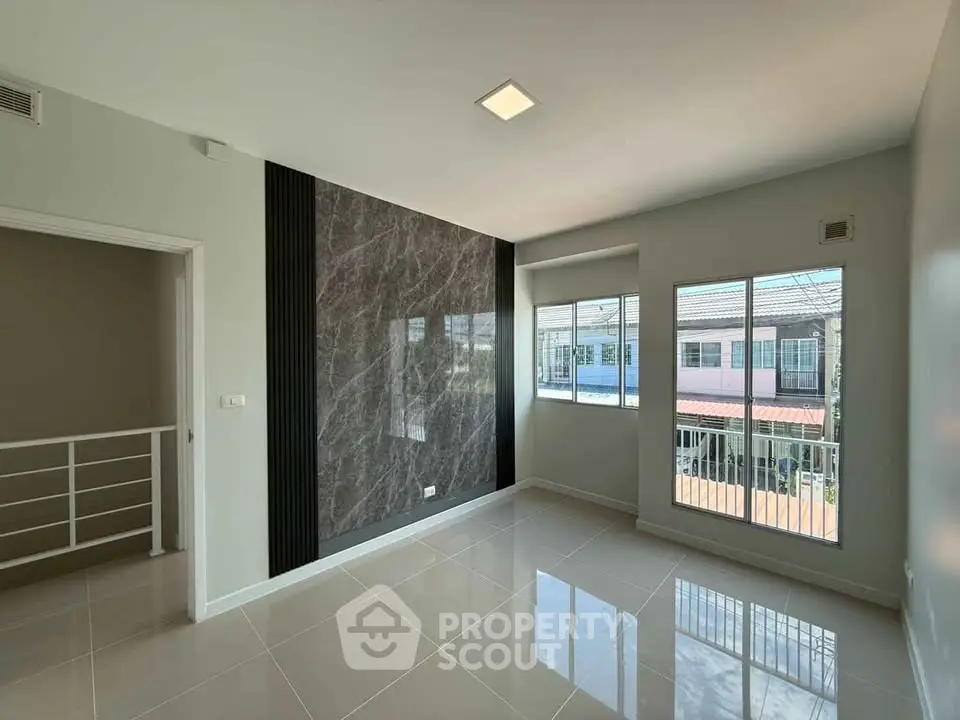 Spacious modern living room with large windows and elegant marble accent wall.