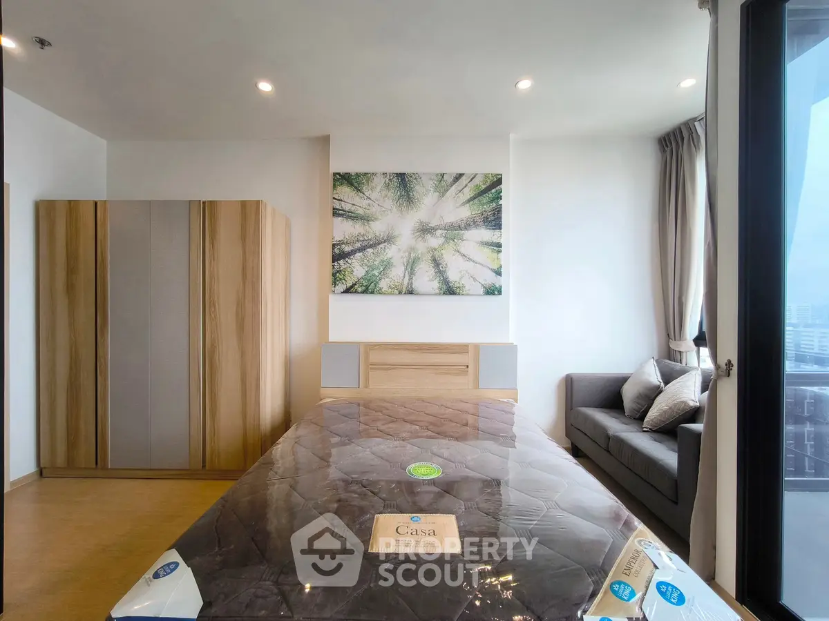 Modern bedroom with stylish decor and city view, featuring a cozy sofa and large wardrobe.