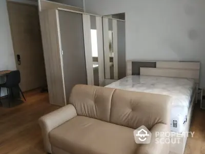 Spacious bedroom with large mirrored wardrobe and comfortable seating area, featuring hardwood floors and modern design.