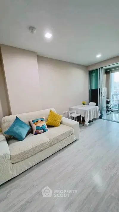 Modern living room with cozy sofa and dining area, featuring a balcony with city view.
