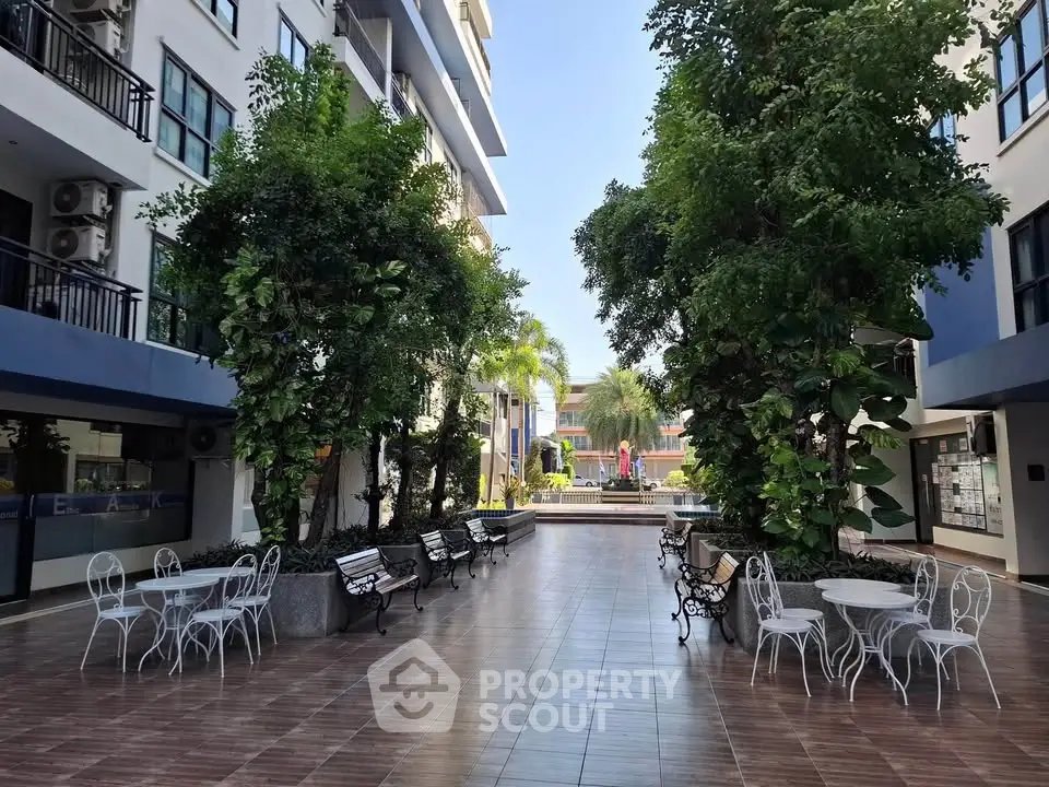 Charming courtyard with lush greenery and seating in modern residential complex.
