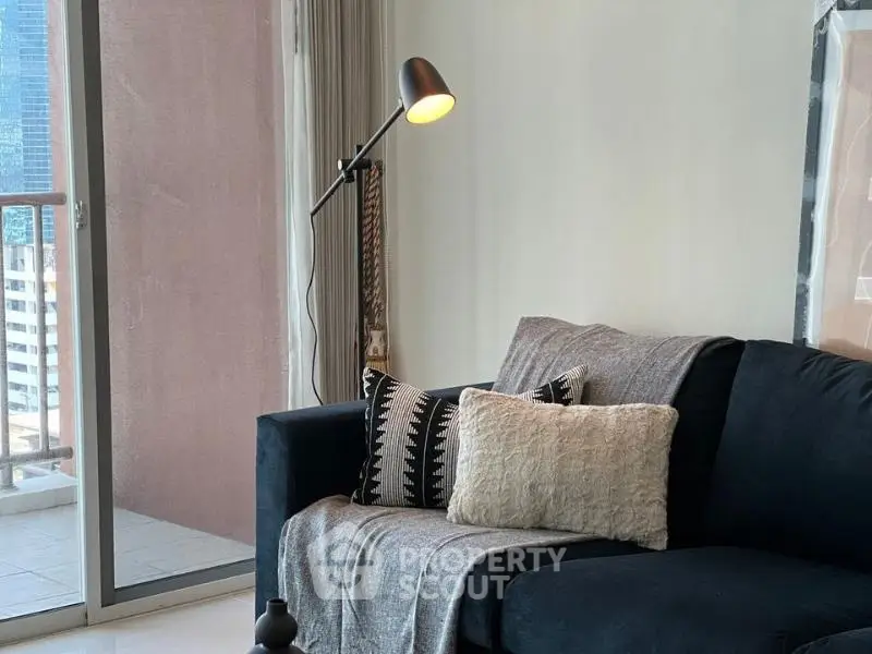 Modern living room with cozy sofa and stylish lamp near balcony with city view.