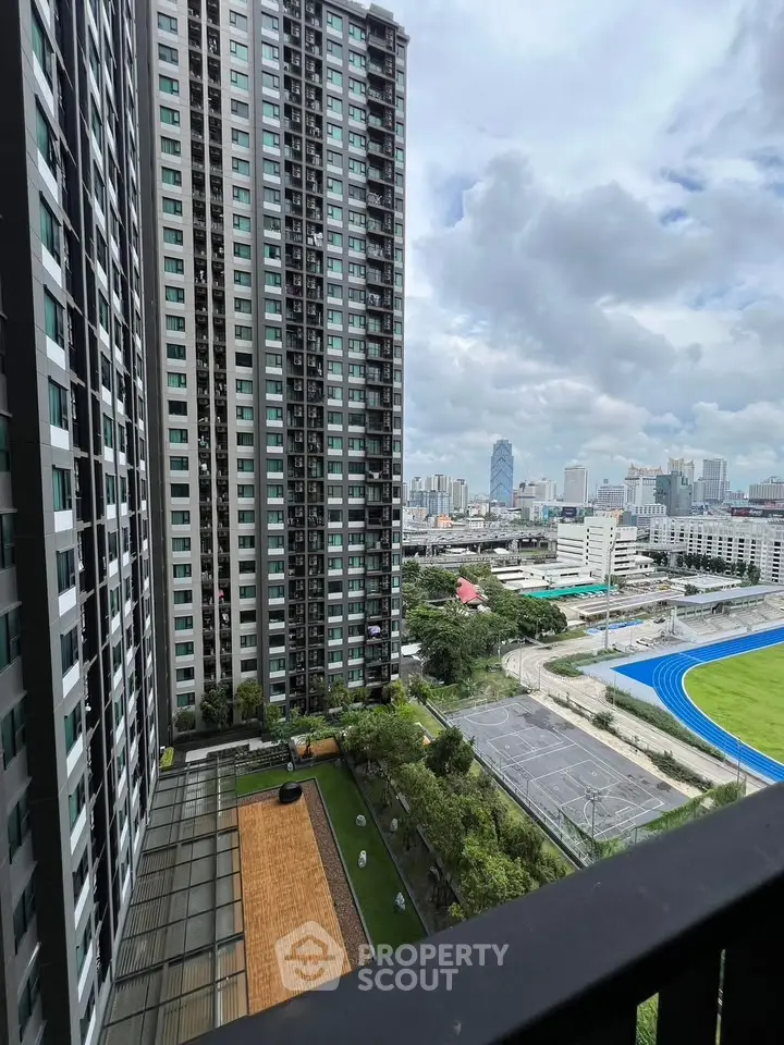 Stunning cityscape view from high-rise balcony overlooking urban skyline and sports field.