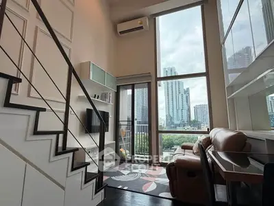 Modern loft apartment with high ceilings and large windows offering city views.