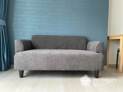 Modern gray sofa in stylish living room with geometric blue accent wall