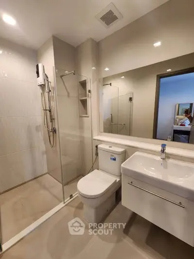 Modern bathroom with glass shower and sleek fixtures in a contemporary apartment.