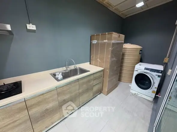 Modern kitchen with gas stove and washing machine in sleek design.