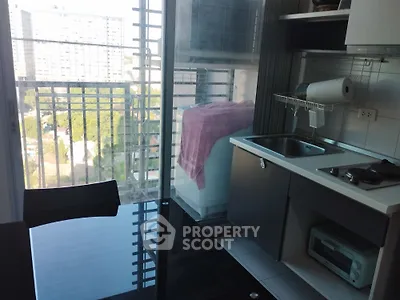 Modern kitchen with sleek design and city view, featuring compact appliances and glass dining table.