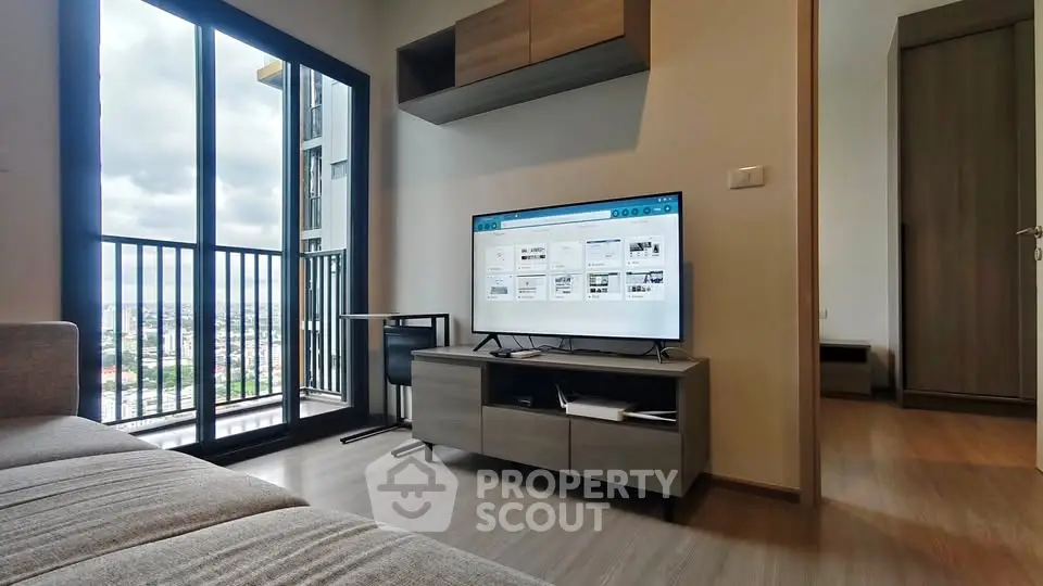 Modern living room with balcony view and sleek furniture in high-rise apartment.