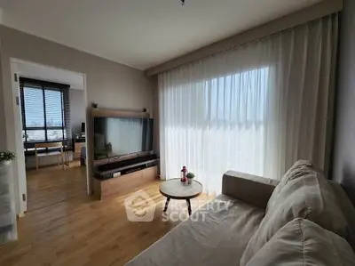 Bright living room with large window and cozy sofa, adjacent to a study area.